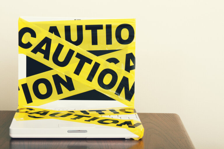 caution tape wrapped around laptop