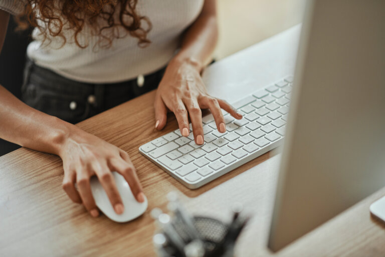 Woman clicks on law firm website in search results. Photo shows one hand on a mouse and the other on the keyboard