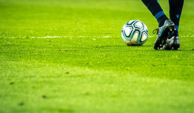 foot of soccer player with soccer ball on green field