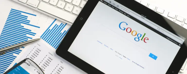 Tablet featuring Google search screen on top of spreadsheets and a keyboard