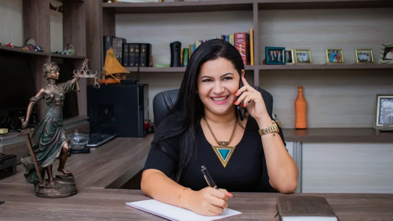 lawyer holding a phone to her ear with pen and paper