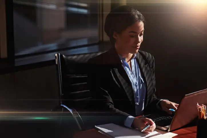 Young Millennial attorney working in office with sunlight on her face