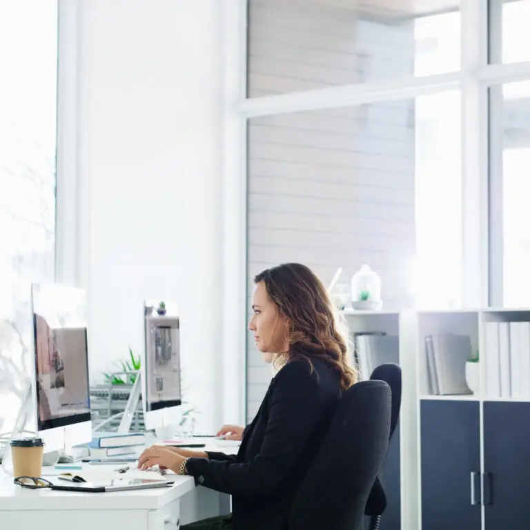 female attorney working on two computers side by side performing a competitor analysis