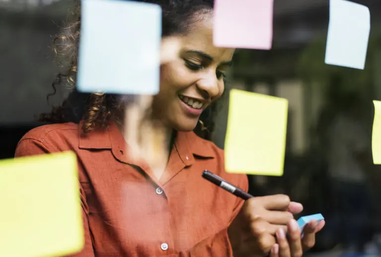 Young attorney writing on post-it notes as she brainstorms taglines for her law firm
