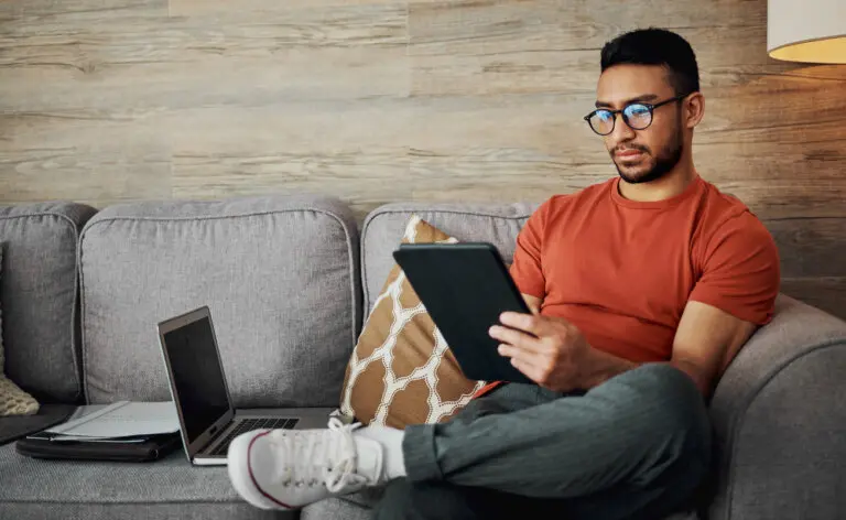 Young man looks at tablet on couch